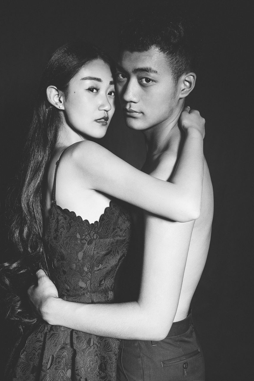 two people, studio shot, looking at camera, togetherness, portrait, waist up, real people, young women, love, lifestyles, embracing, standing, young adult, bonding, happiness, smiling, leisure activity, friendship, touching, women, fashion model, beautiful woman, arm around, black background, outdoors, day, people
