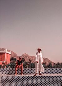 Men standing on rock against sky