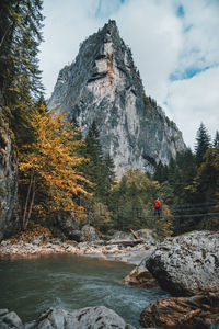 Full length of man standing on footbridge over river against mountain