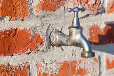 Close-up of old faucet against wall