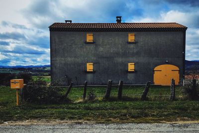 Built structure on field against cloudy sky