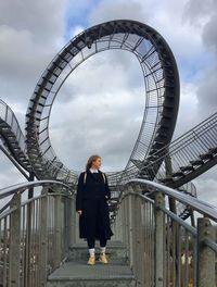 Woman standing on bridge against spiral staircases