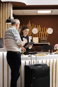 Side view of young woman standing by table