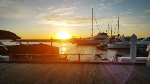 Boats moored at harbor against sky during sunset