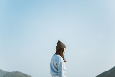 Low angle view of woman standing against clear sky