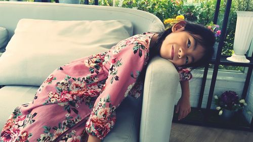 Smiling girl lying on sofa at home