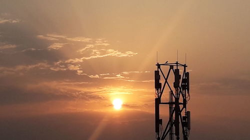 Silhouette cranes against sky during sunset