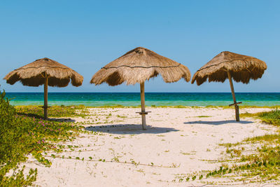 Lounge chairs on beach against clear sky