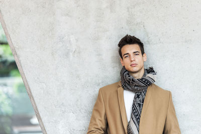 Portrait of young man standing against wall