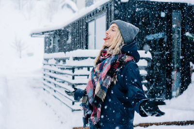 A young woman sticks out her tongue to catch snowflakes during a snow storm.