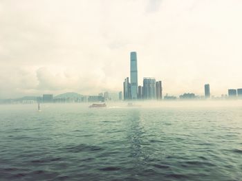 Victoria harbor against modern buildings in foggy weather