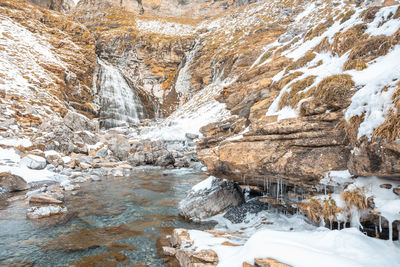 Stream flowing through rocks during winter