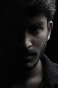 Close-up portrait of young man against black background