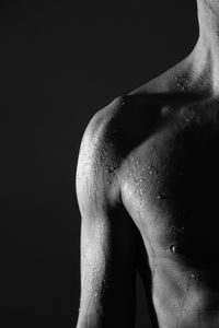 Midsection of shirtless man against black background