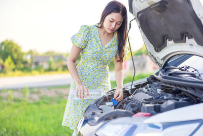 Young woman standing by car