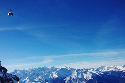 Scenic view of snow covered mountains against blue sky