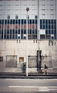 Full length of girl walking on footpath against wall