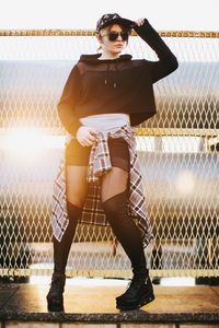 Portrait of young woman standing against chainlink fence.construction net. korean fashion. european.