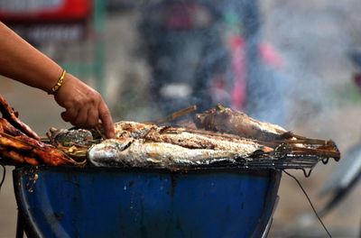 Person preparing meat on barbecue grill