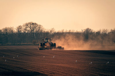 Tractor on agricultural field against clear sky