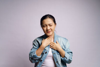Smiling young woman standing against gray background