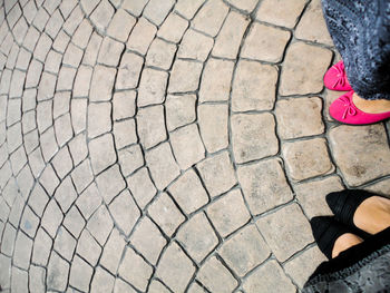 Low section of woman standing on cobblestone