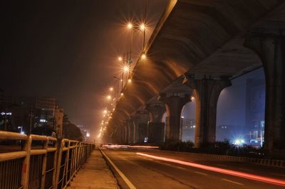 Light trails on illuminated city against clear sky at night