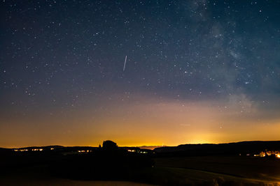 Silhouette field against sky at night