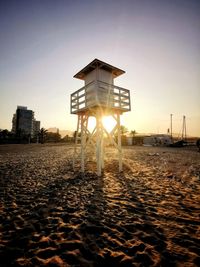 Lifeguard hut on beach against sky during sunset