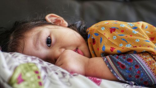 Portrait of cute baby girl lying on bed at home