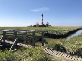 Lighthouse on field against sky