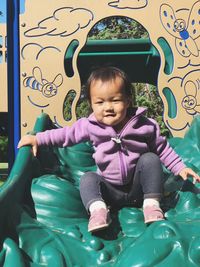 Cute boy sitting on slide at playground