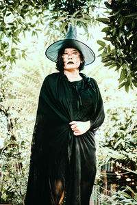 Young woman looking away while standing against plants