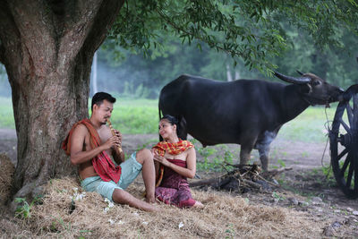 Men eating man sitting on tree