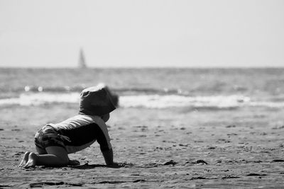 Full length of woman relaxing on beach against sky
