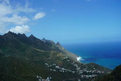 Scenic view of sea and mountains against blue sky