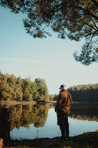 Rear view of man standing by tree against sky
