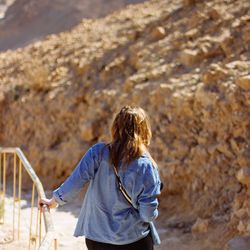 Rear view of woman standing by railing on mountain