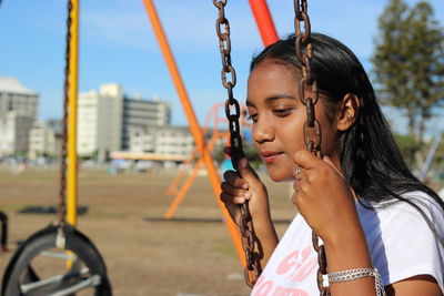 Young woman sitting on swing at playground