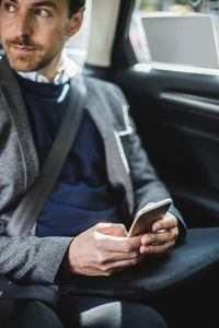 Mature businessman looking away while using phone in car