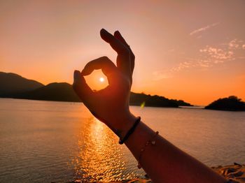 Silhouette woman with arms raised against sky during sunset