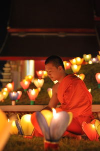 Side view of young man sitting at night