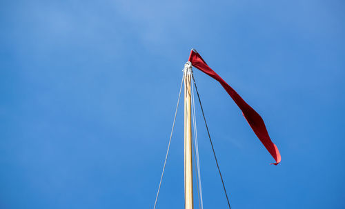 Low angle view of flags against clear blue sky