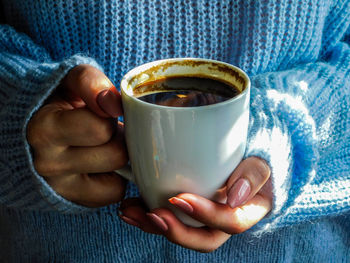 Midsection of man holding coffee cup