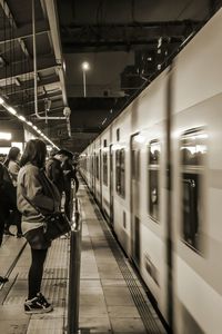 Rear view of woman at railroad station at night