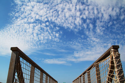 Low angle view of footbridge railing against sky