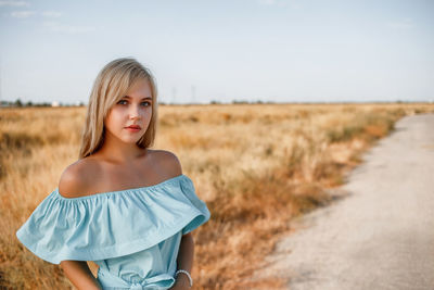 Portrait of teenage girl wearing dress standing on land against sky