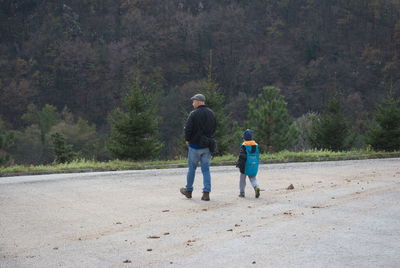 Rear view of father and son walking on road