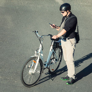 High angle view of businessman using mobile phone while riding bicycle on road