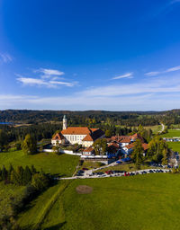 Houses on field by buildings against blue sky